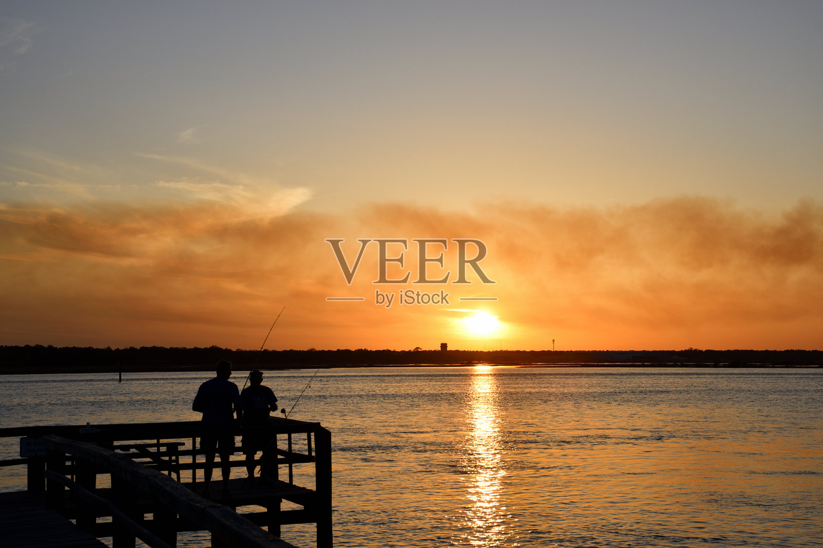 日落时分，人们在码头上钓鱼照片摄影图片