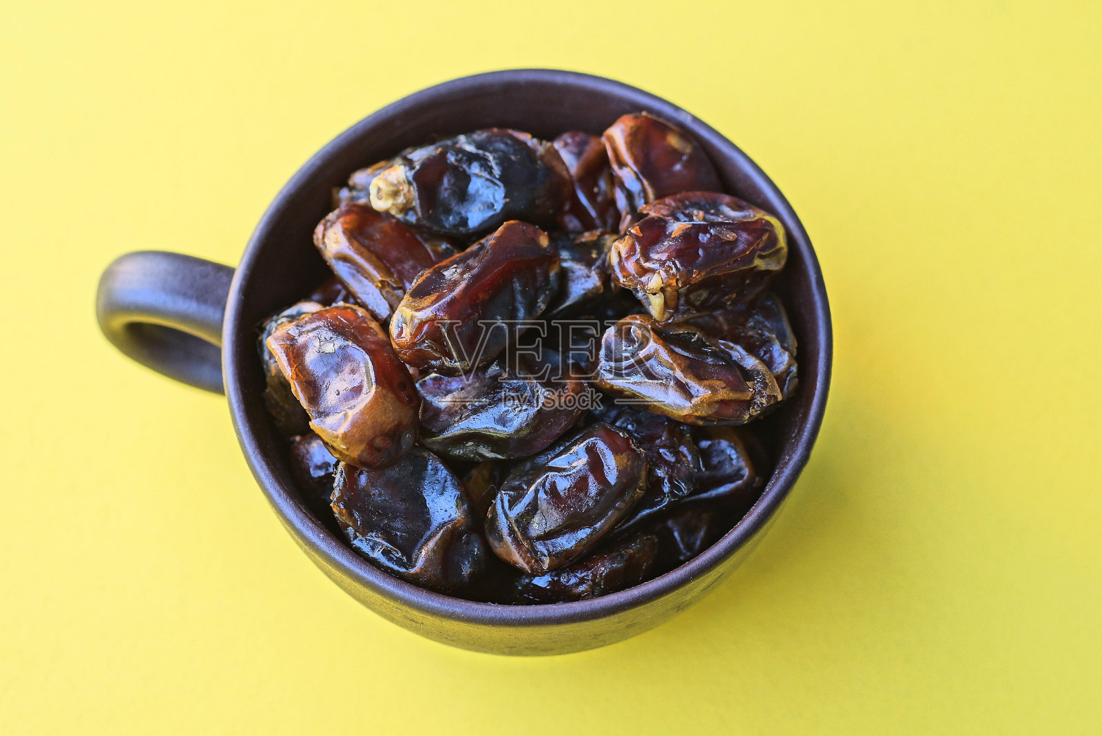 一堆干果枣在一个棕色的陶瓷杯照片摄影图片