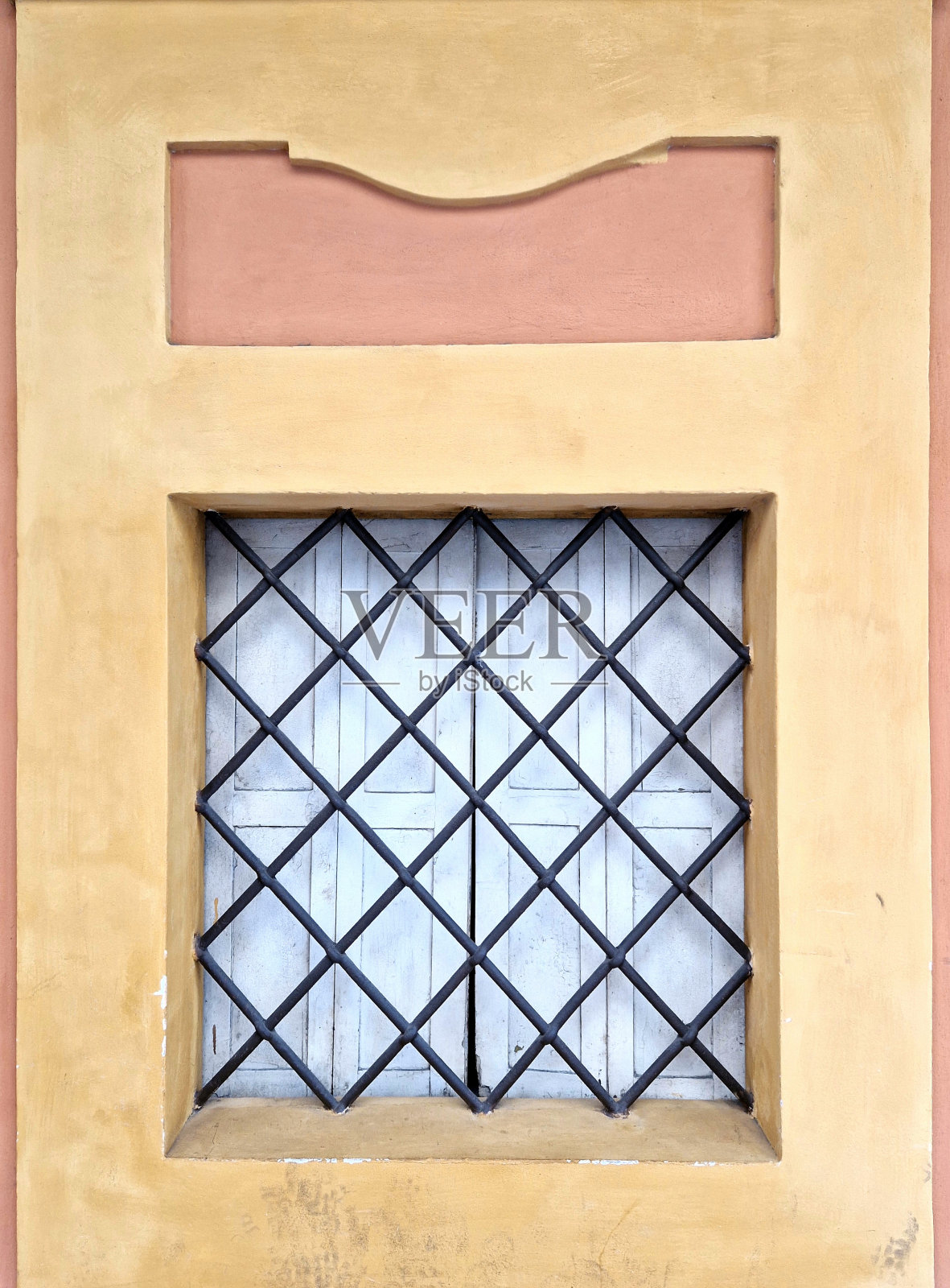 意大利城市街道上的墙特写——金属栏杆交叉在带百叶窗的窗户前照片摄影图片