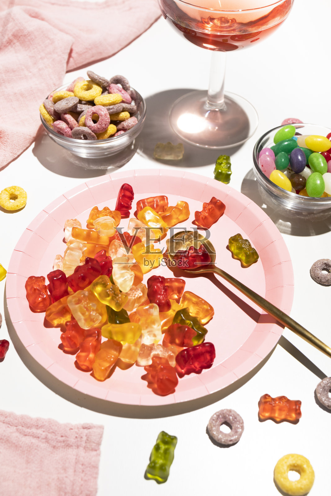 盘子里有小熊软糖，糖豆和一杯粉红色的饮料。给食物上色。聚会和庆祝活动照片摄影图片