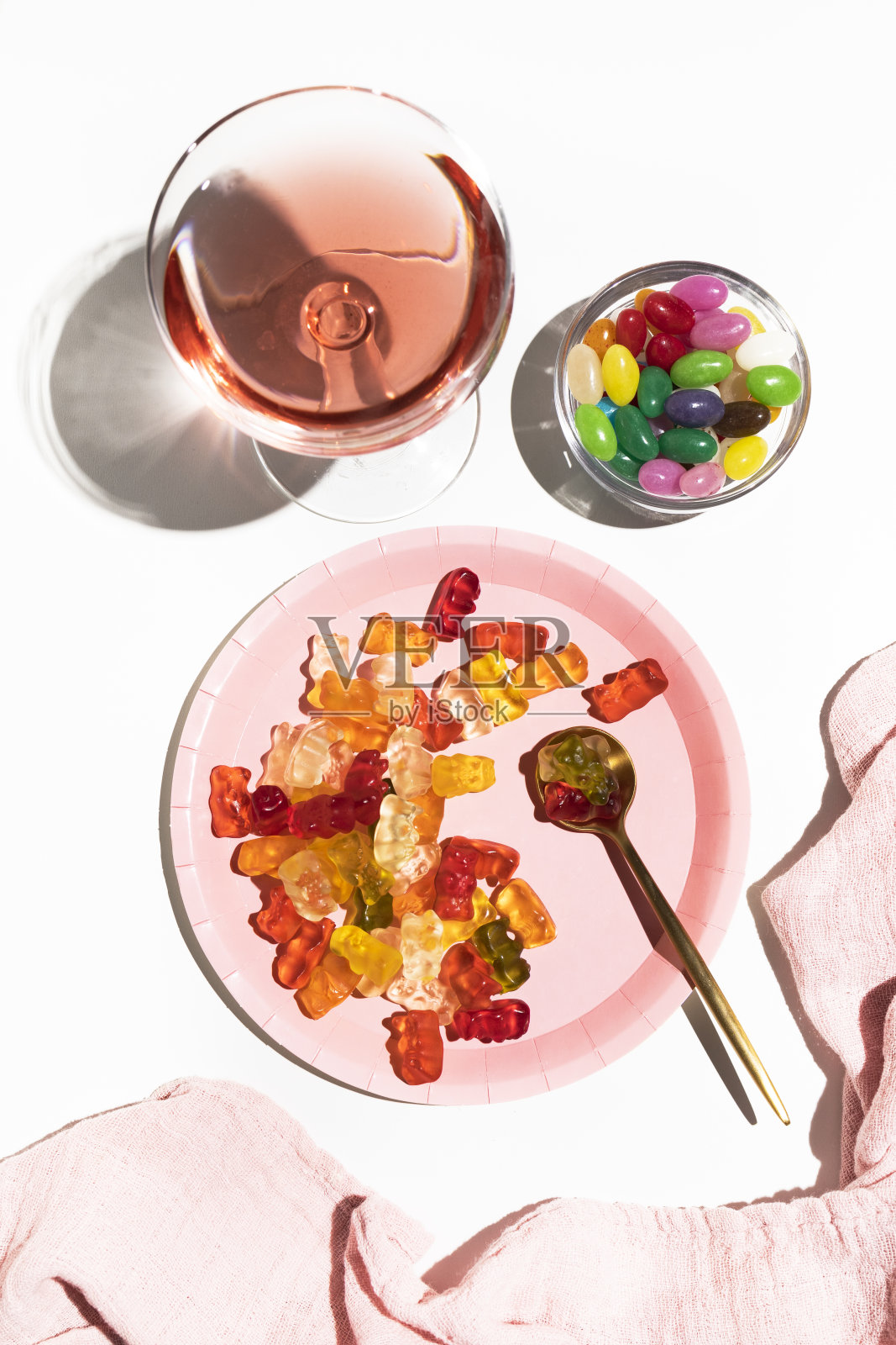 盘子里有小熊软糖，糖豆和一杯粉红色的饮料。给食物上色。聚会和庆祝活动照片摄影图片