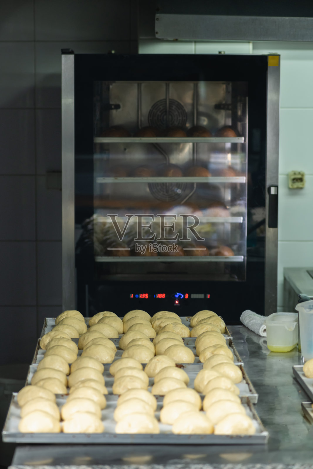 把面团放在烤盘里，放进餐厅的烤箱照片摄影图片