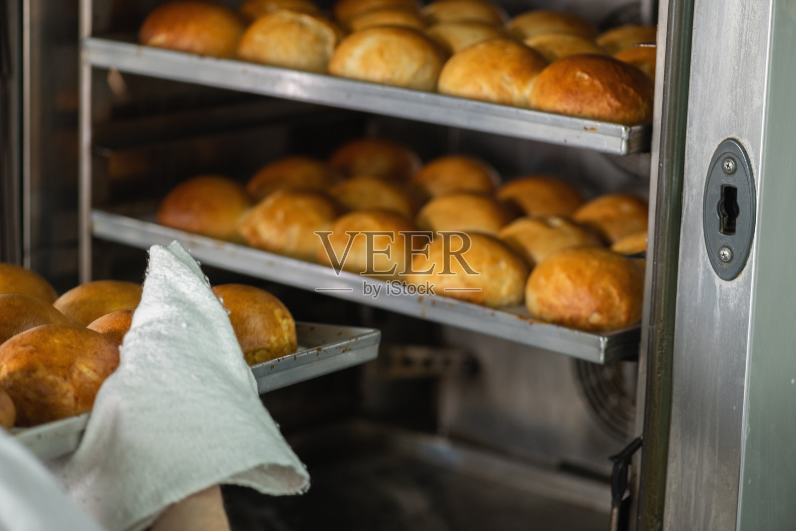 面包师把烤好的面包从烤箱里拿出来照片摄影图片