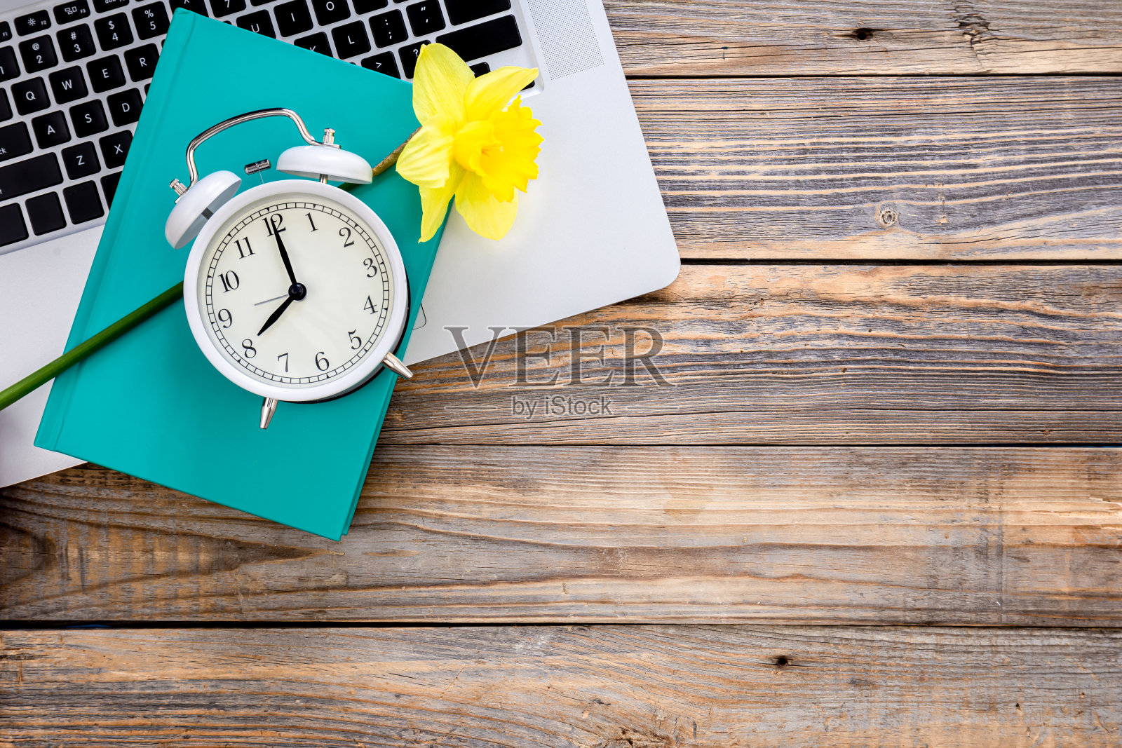 笔记本电脑，书，花和白色闹钟木制背景，俯视图。照片摄影图片