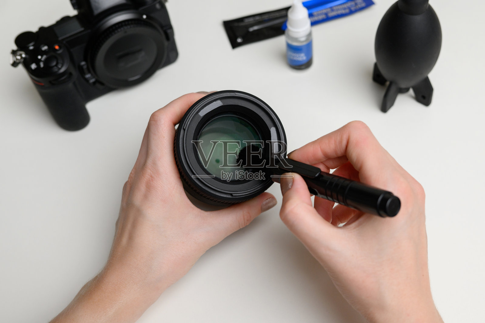 用专用的清洁刷清洁数码相机镜头上的灰尘照片摄影图片