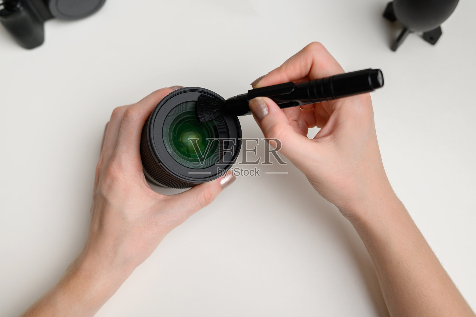 用专用的清洁刷清洁数码相机镜头上的灰尘照片摄影图片