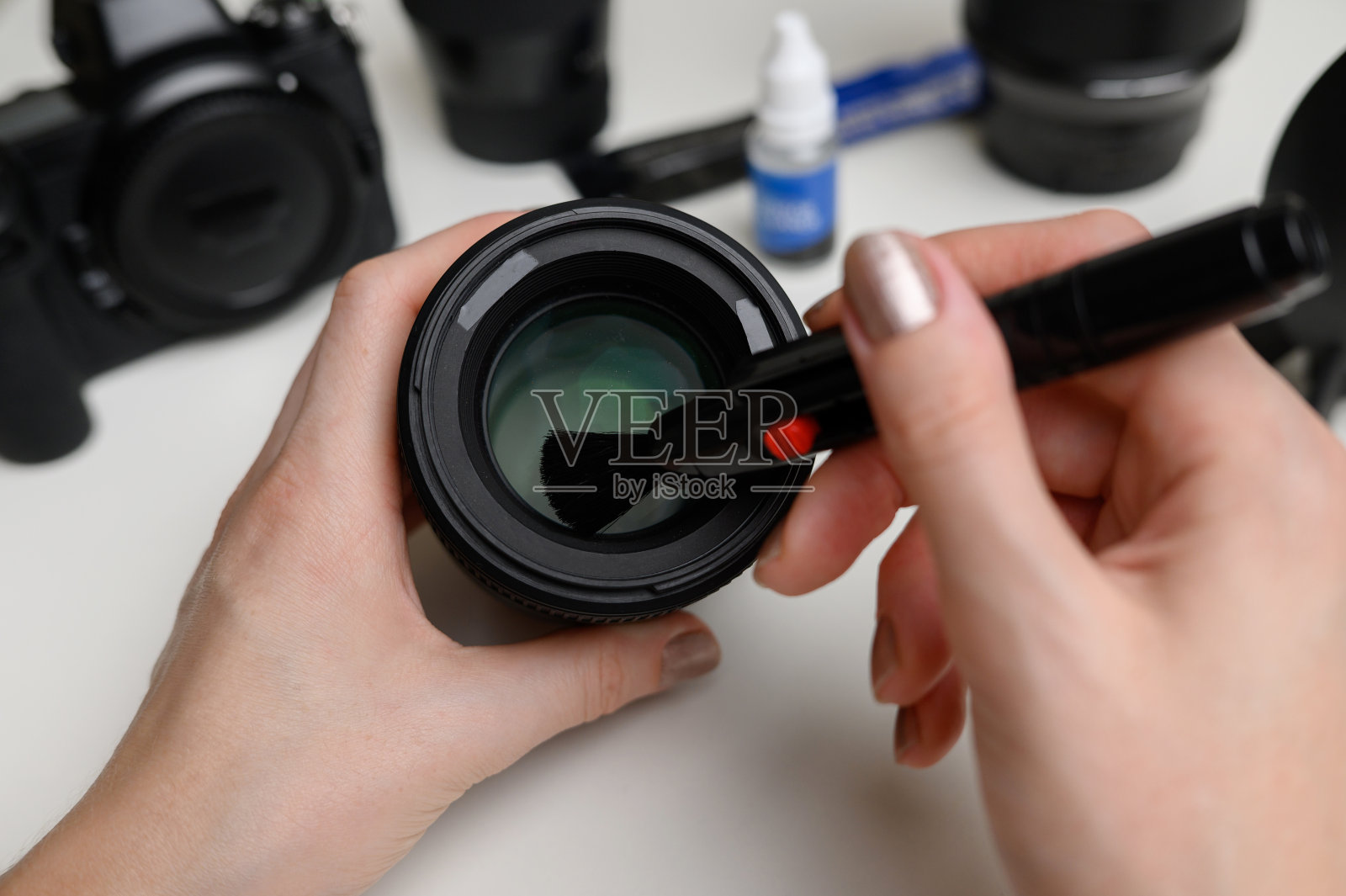 用专用的清洁刷清洁数码相机镜头上的灰尘照片摄影图片