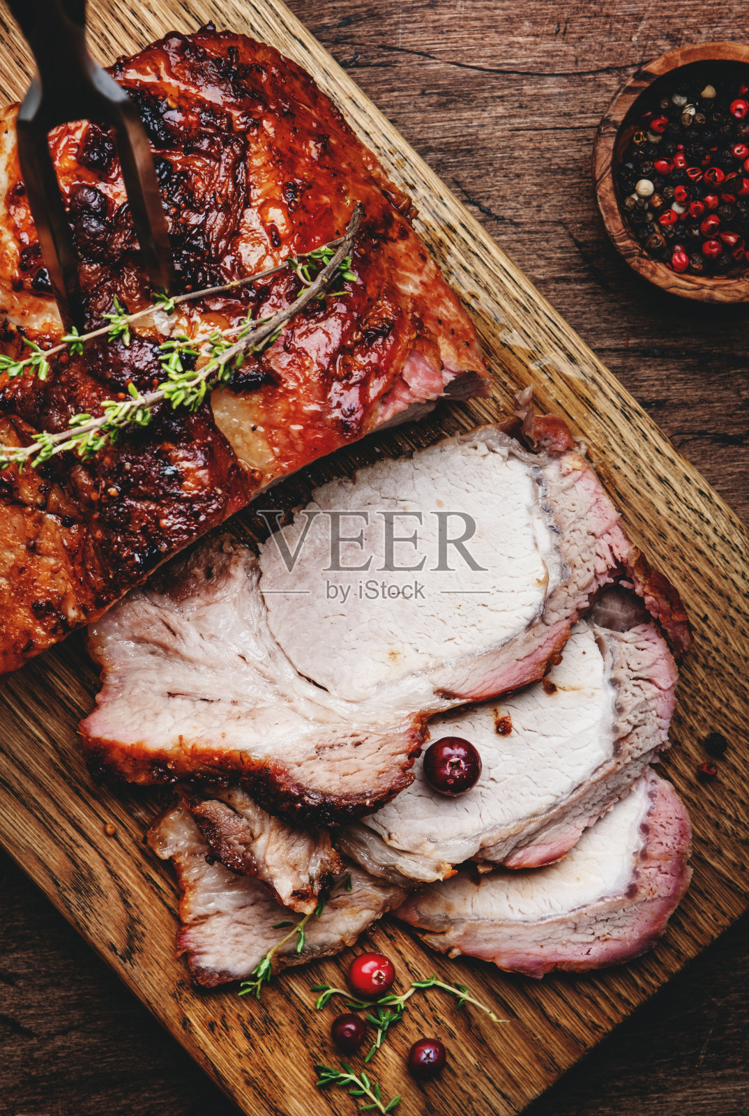 烤猪腰肉在质朴的木制砧板与香料，香草和蔓越莓。木质厨房餐桌背景，俯视图照片摄影图片