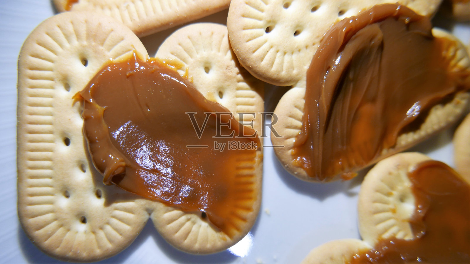 桌上的糖果:饼干上的牛奶焦糖，上角度，特写。牛奶焦糖饼干。上面有牛奶焦糖的饼干照片摄影图片