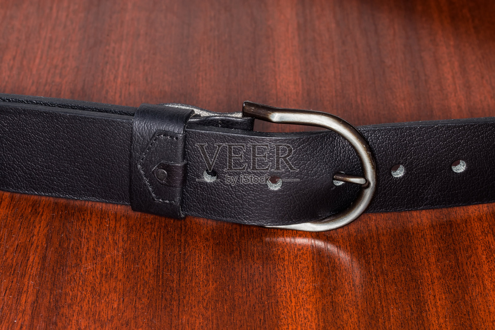 在木桌上系好带半圆形框架扣的皮带照片摄影图片