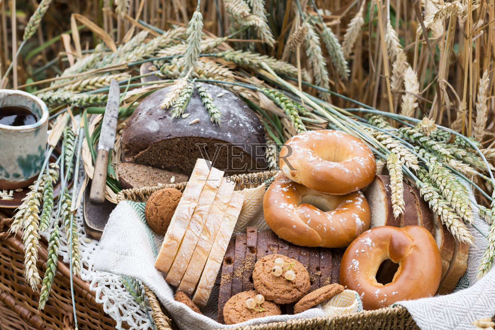 各种各样的面包和其他糕点在柳条托盘上的花边桌布小麦穗照片摄影图片