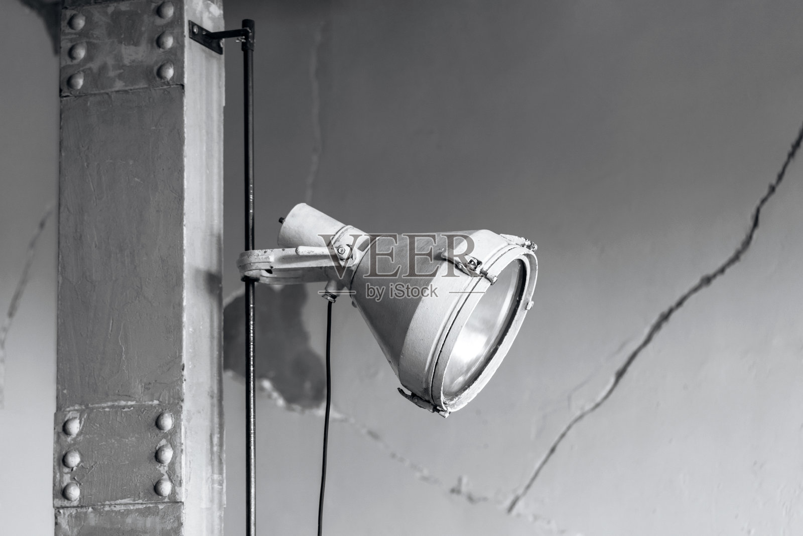 极简工业风格的灰色金属照明灯在灰色支柱和开裂的墙壁背景。照片摄影图片