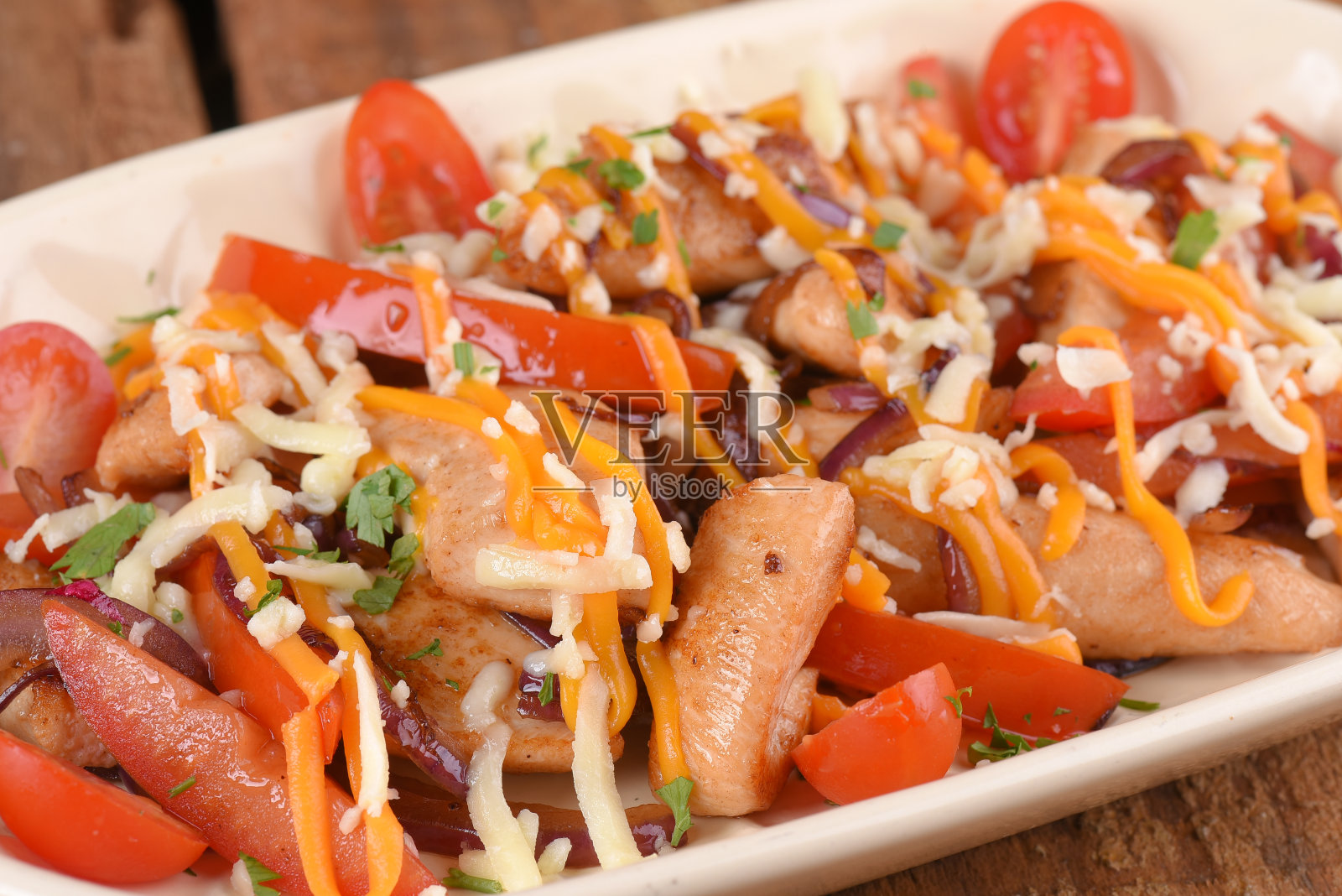 炸鸡配马苏里拉干酪、切达干酪、圣女果和焦糖洋葱，木桌美味照片摄影图片