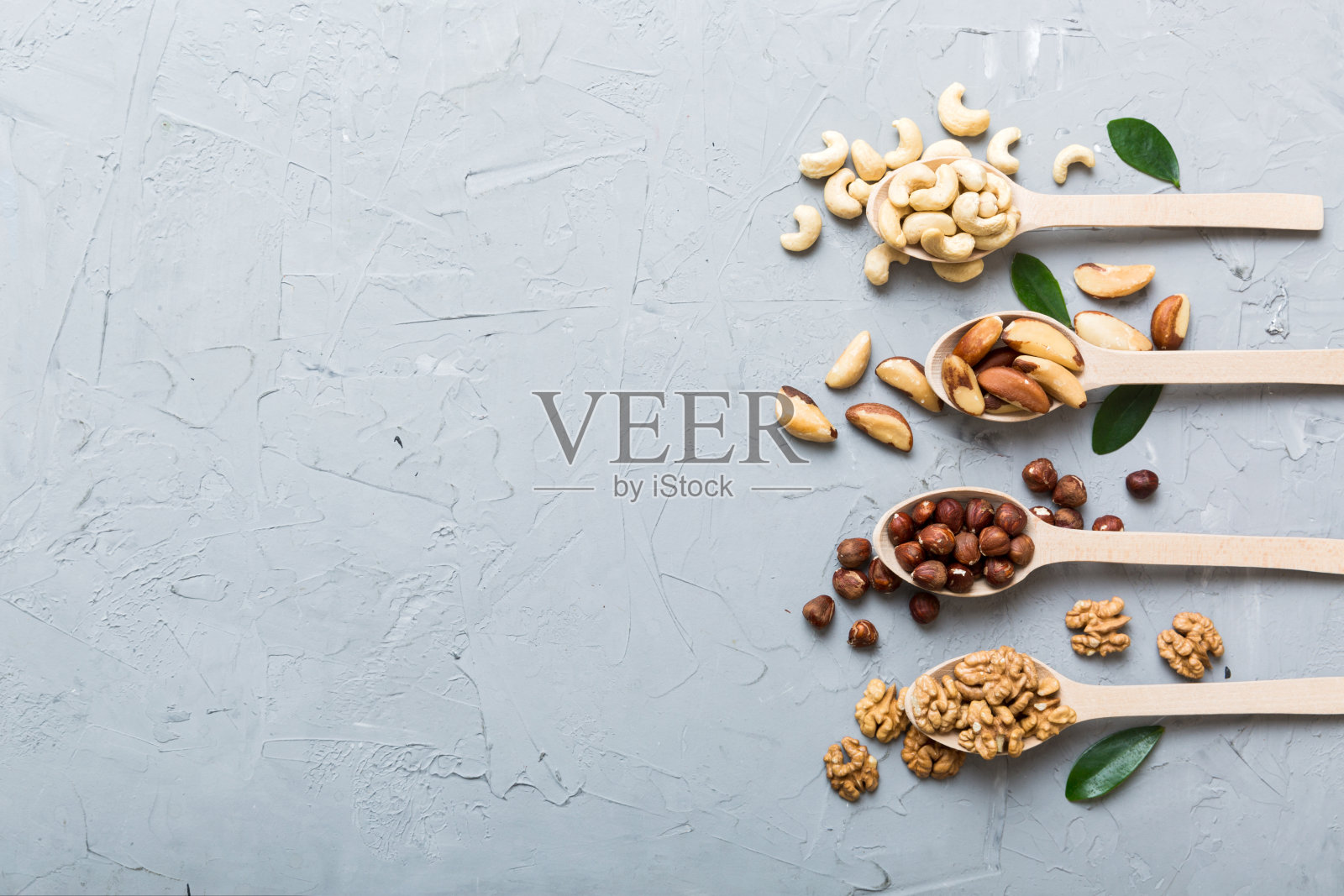 用白色木勺混合坚果。在彩色背景上混合各种坚果。开心果、腰果、核桃、榛子、花生和巴西坚果照片摄影图片