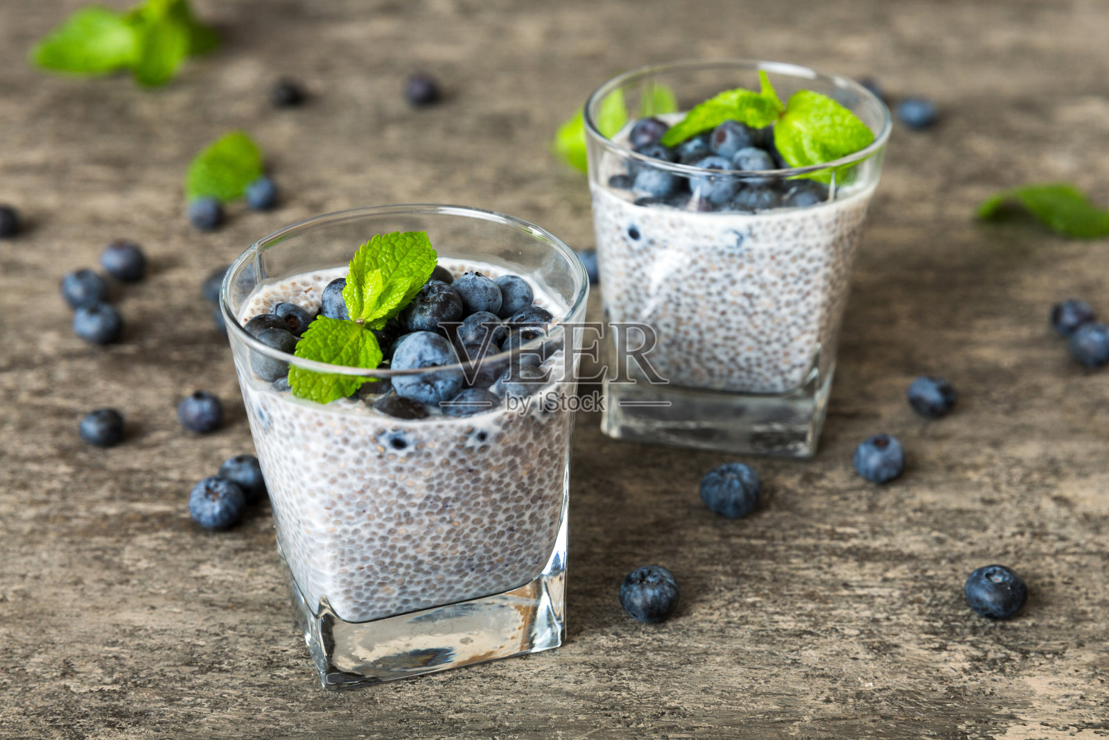 健康早餐或早餐以奇亚籽香草布丁和蓝莓浆果为餐桌背景，素食，饮食和健康理念。椰奶蓝莓奇亚布丁照片摄影图片