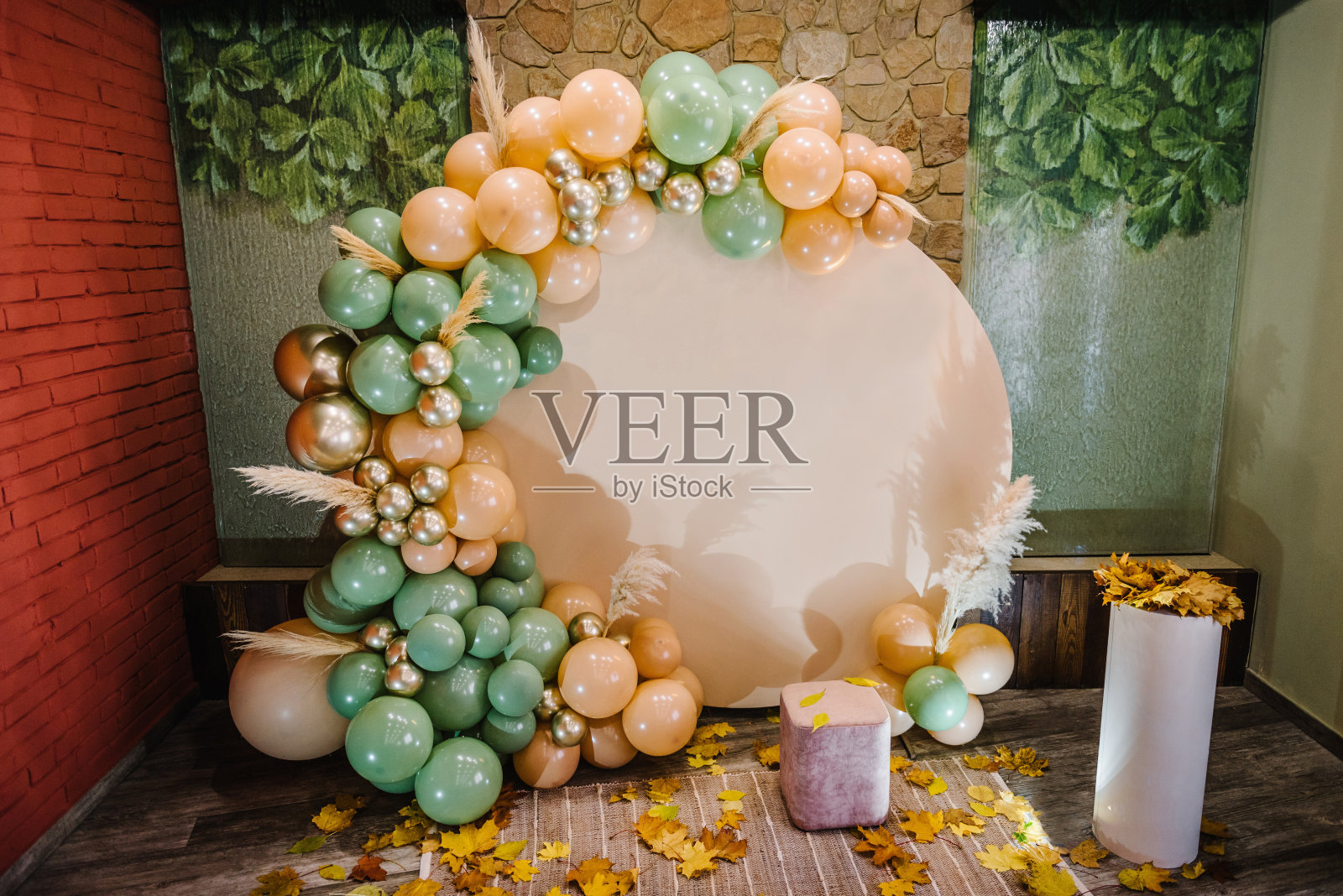 生日宴会上的招待会。拱门上装饰着绿色、棕色、金色的气球，干燥的秋叶用于婚礼仪式。庆祝洗礼。时髦的秋季装饰。照片墙装饰空间，文字的地方照片摄影图片