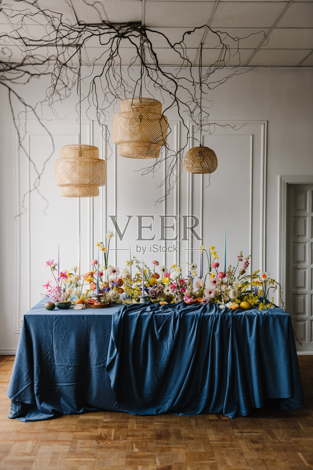 节日的餐桌上装饰着鲜花、水果、绿色植物、蜡烛和挂灯、干树枝。生日庆祝活动。家庭度假在现代餐厅。时尚的春季派对。家庭内部。照片摄影图片