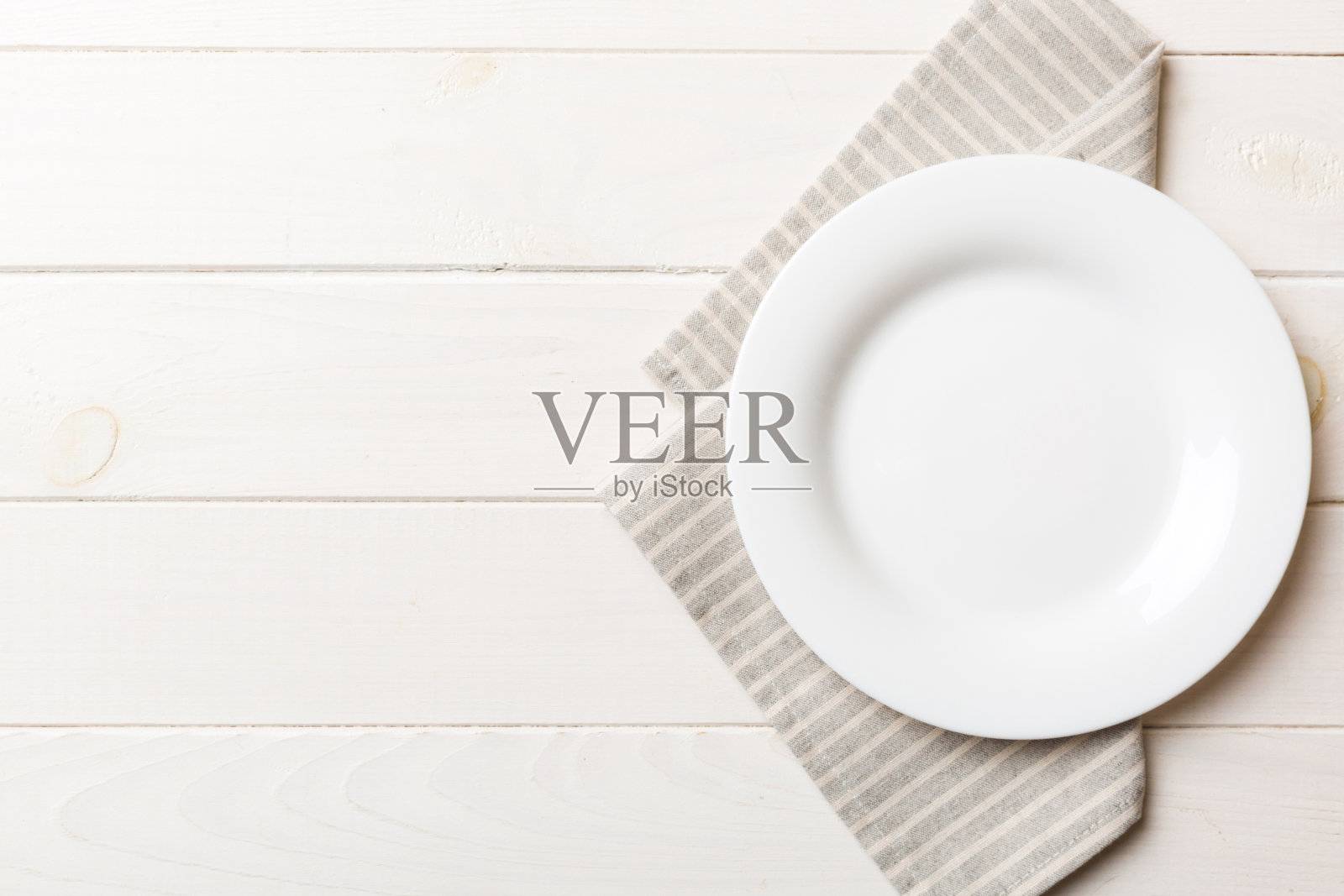 彩色背景上的俯视图，桌布上的空圆形白色盘子盛食物。空盘子放在餐巾上，为你的设计留出空间照片摄影图片