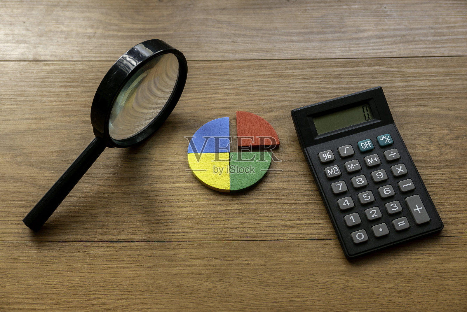 季度报告概念。公司财务报告。商业图表。彩色四分之一木制饼图件与计算器。照片摄影图片