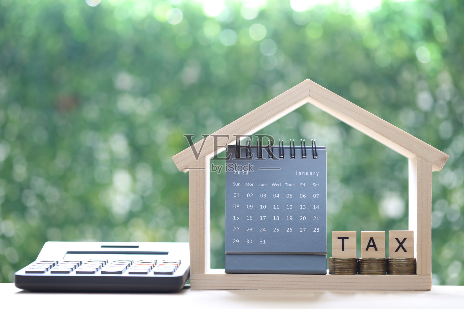税收概念，样板房日历，绿色背景上的一叠硬币和税字，商业投资和财产税概念照片摄影图片