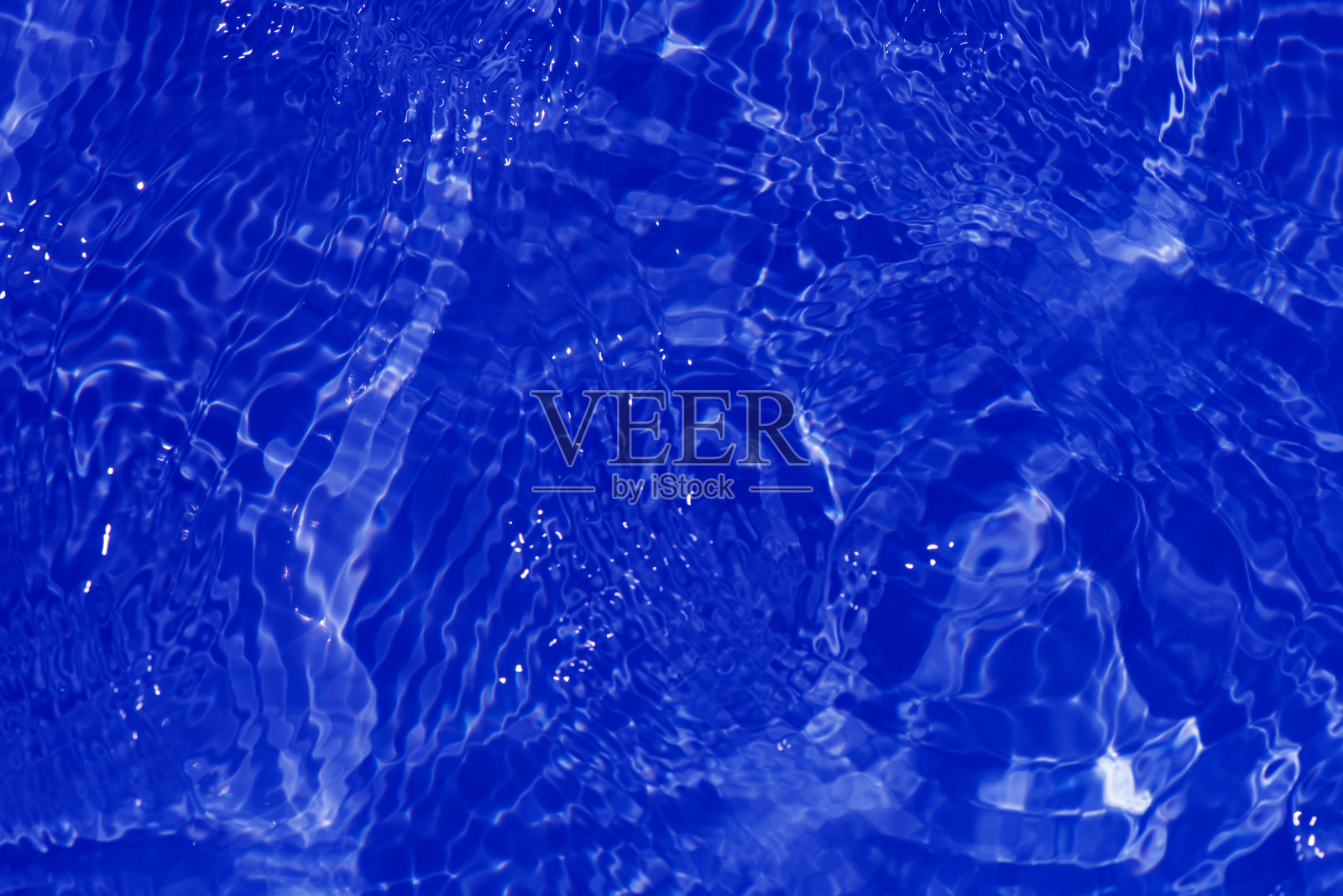 蓝蓝的水面上泛起涟漪。散焦模糊透明蓝色透明平静水面纹理与飞溅和气泡。水波与闪亮的图案纹理背景。照片摄影图片