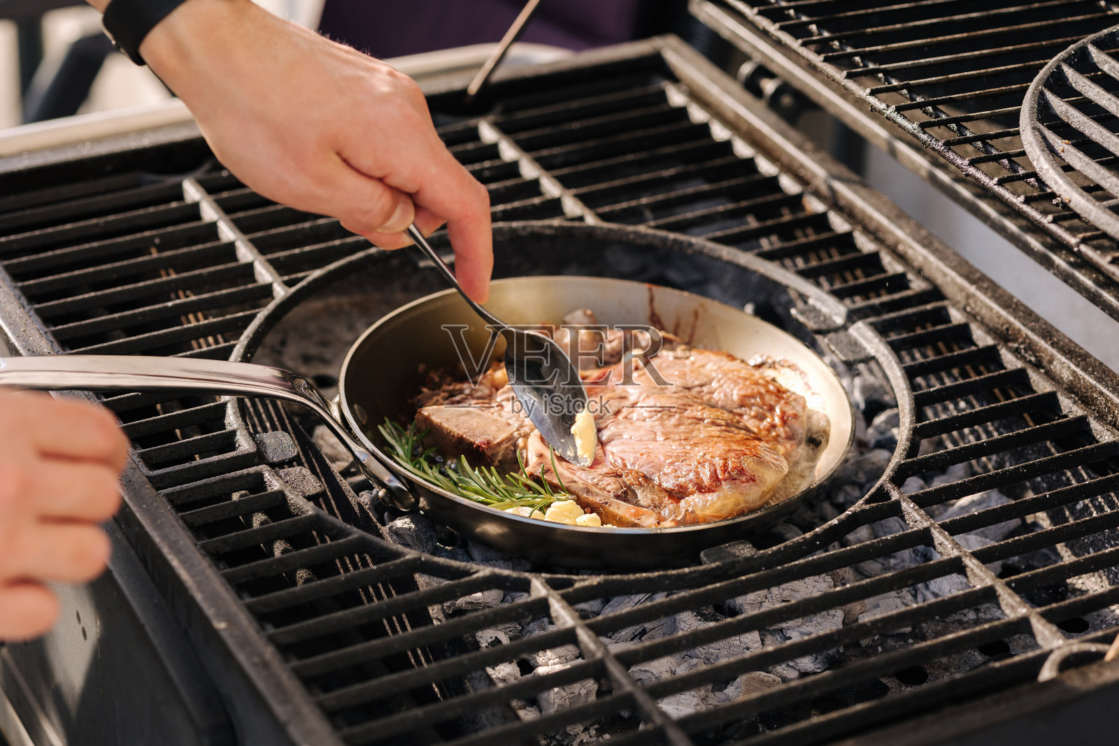 男厨师在室外烤架上的碳钢煎锅上准备t骨牛排。烧烤的概念。特写镜头照片摄影图片