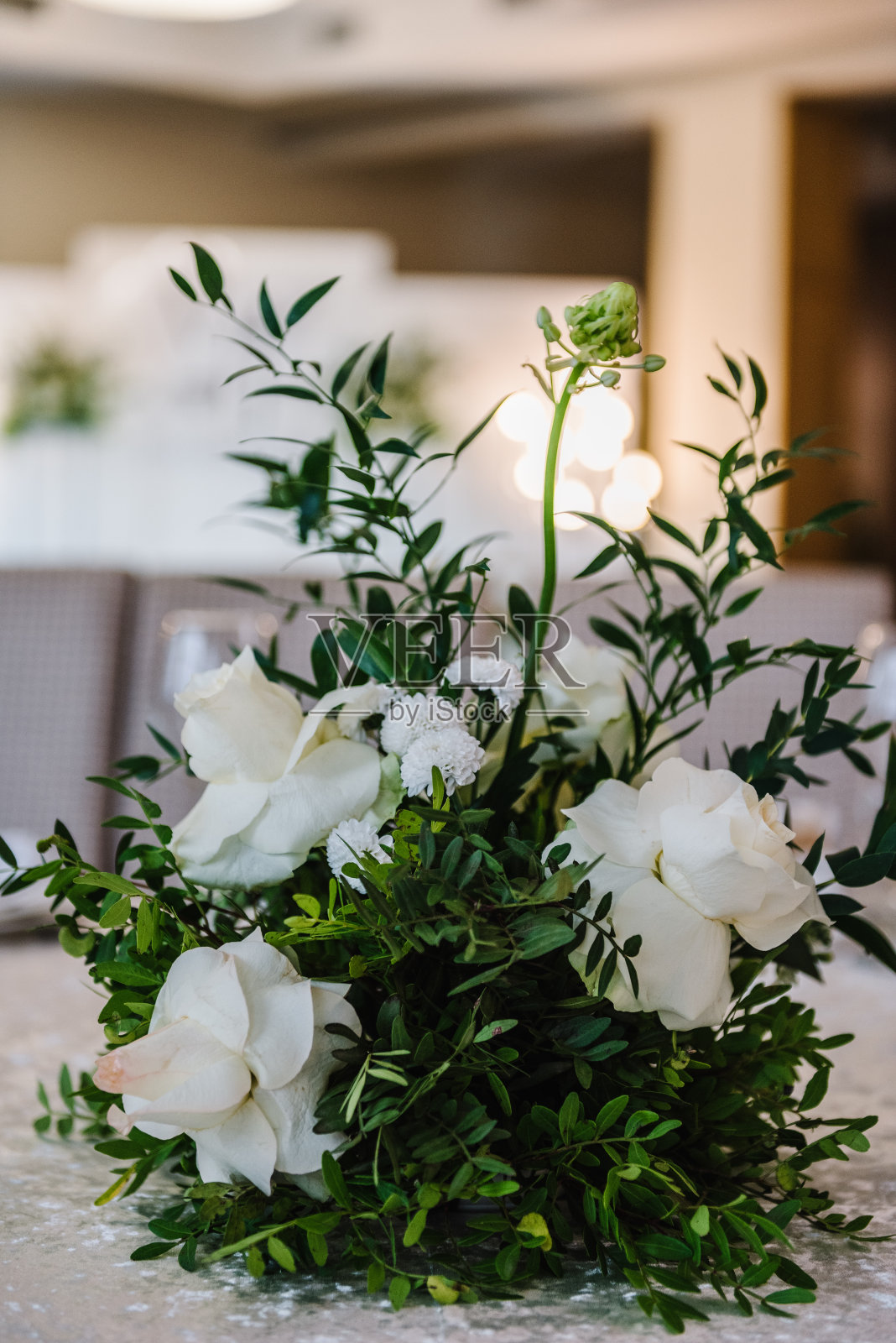 花的构图与玫瑰，绿叶和蜡烛在桌子的中心。婚礼布置，餐桌接待。装饰特写。餐厅内部。照片摄影图片