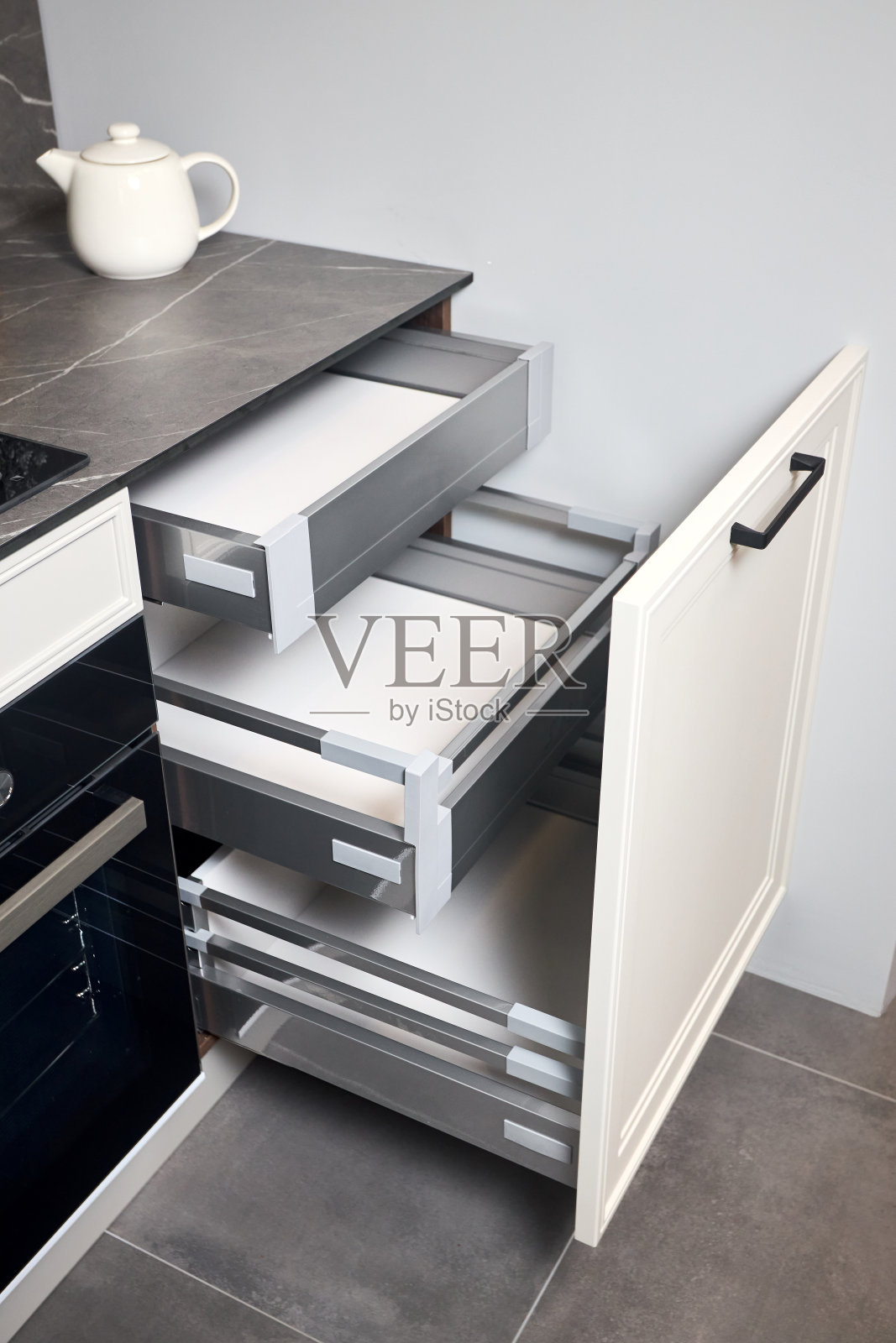 煤气灶黑色玻璃和铁滚刀在大理石轻石材台面水平滑动拉出抽屉货架存储在厨房橱柜。照片摄影图片