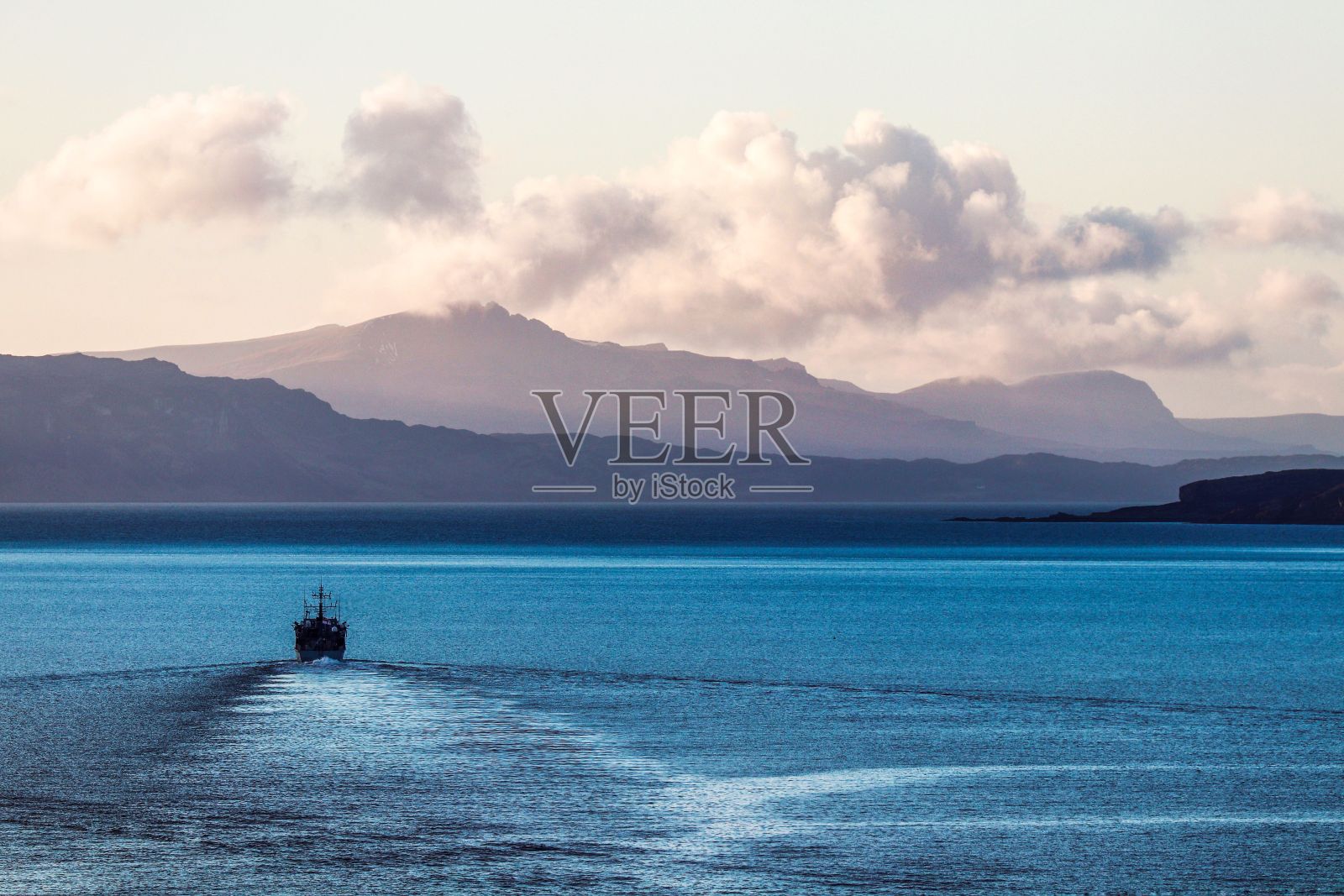 鸟瞰一艘大型船只在蓝色的水面上航行，靠近英国苏格兰洛查尔什凯尔的山脉照片摄影图片