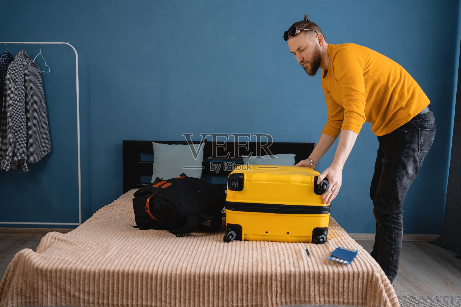 度假旅游的概念。动身前，年轻人在床上收拾夏季旅行的行李。准备假期旅行。旅游，人和行李的概念照片摄影图片