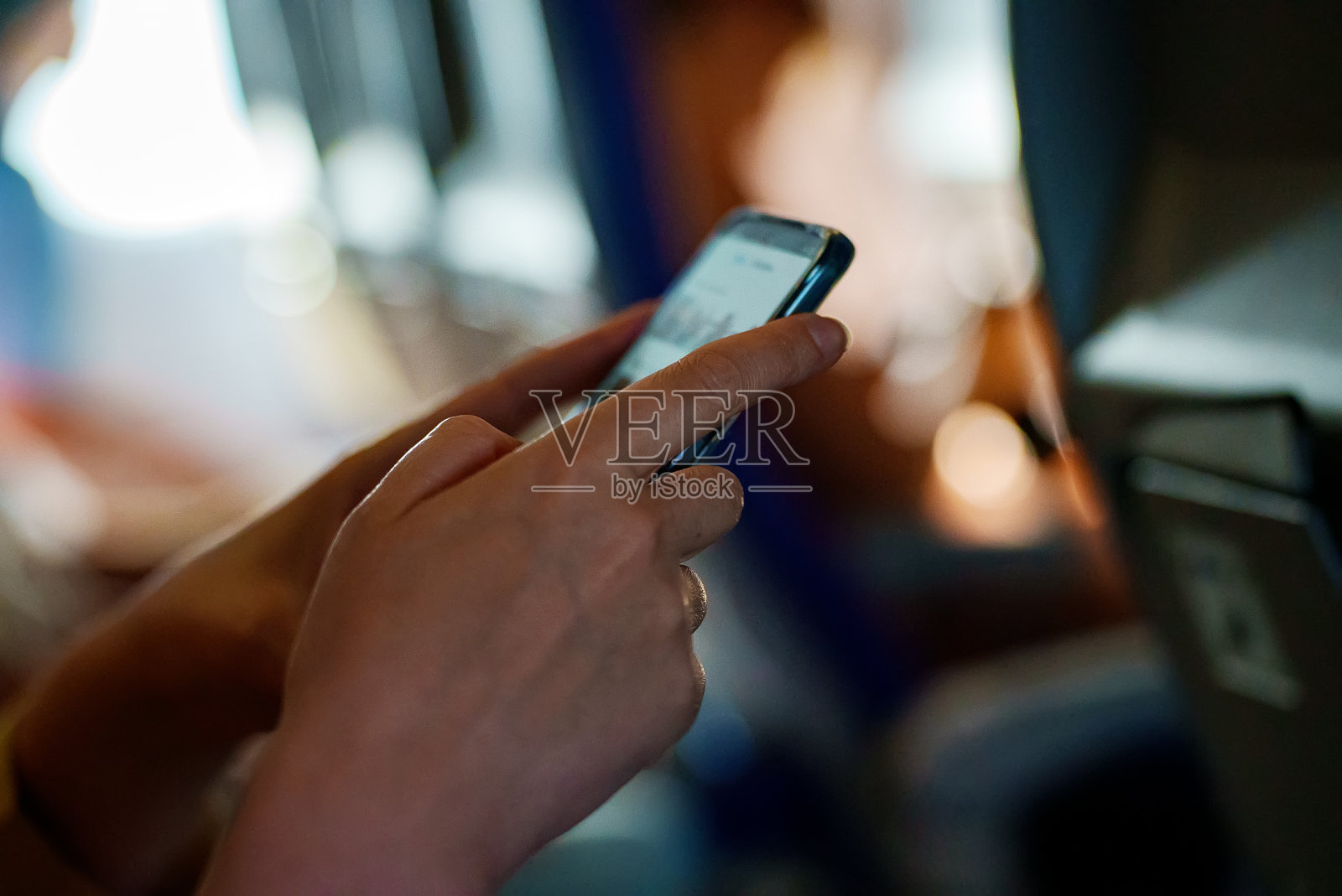 一位女士在飞机上使用智能手机。照片摄影图片