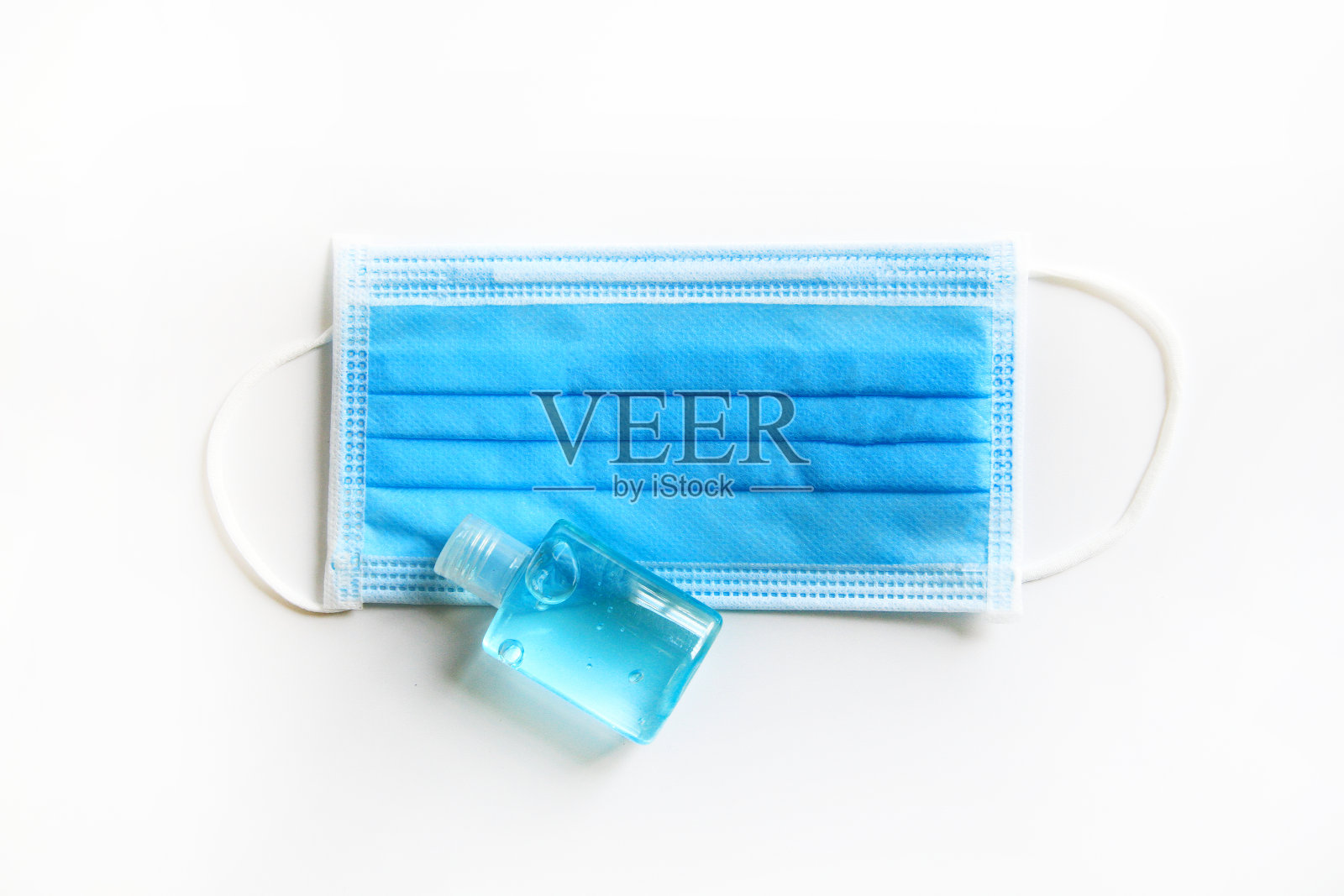 面部医生或医用口罩的俯视图，与白色背景隔离的一瓶酒精凝胶照片摄影图片