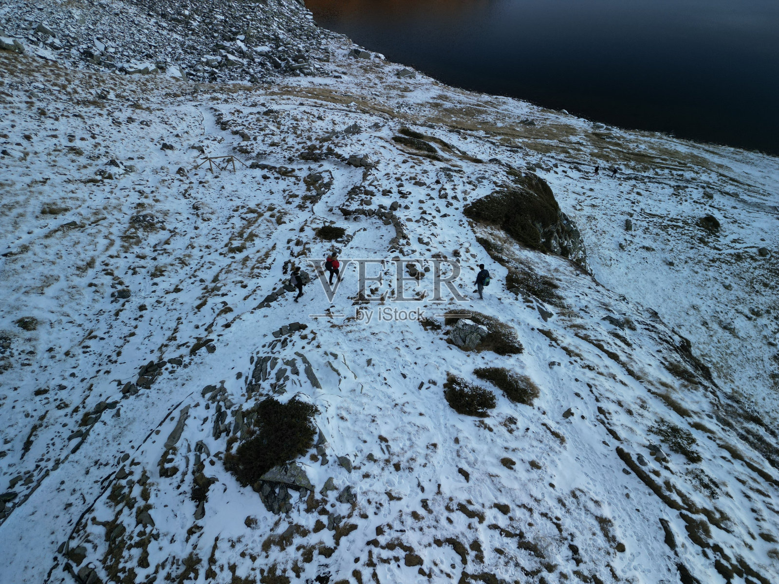 白雪皑皑的冬景，山腰上点缀着湖边的岩石照片摄影图片