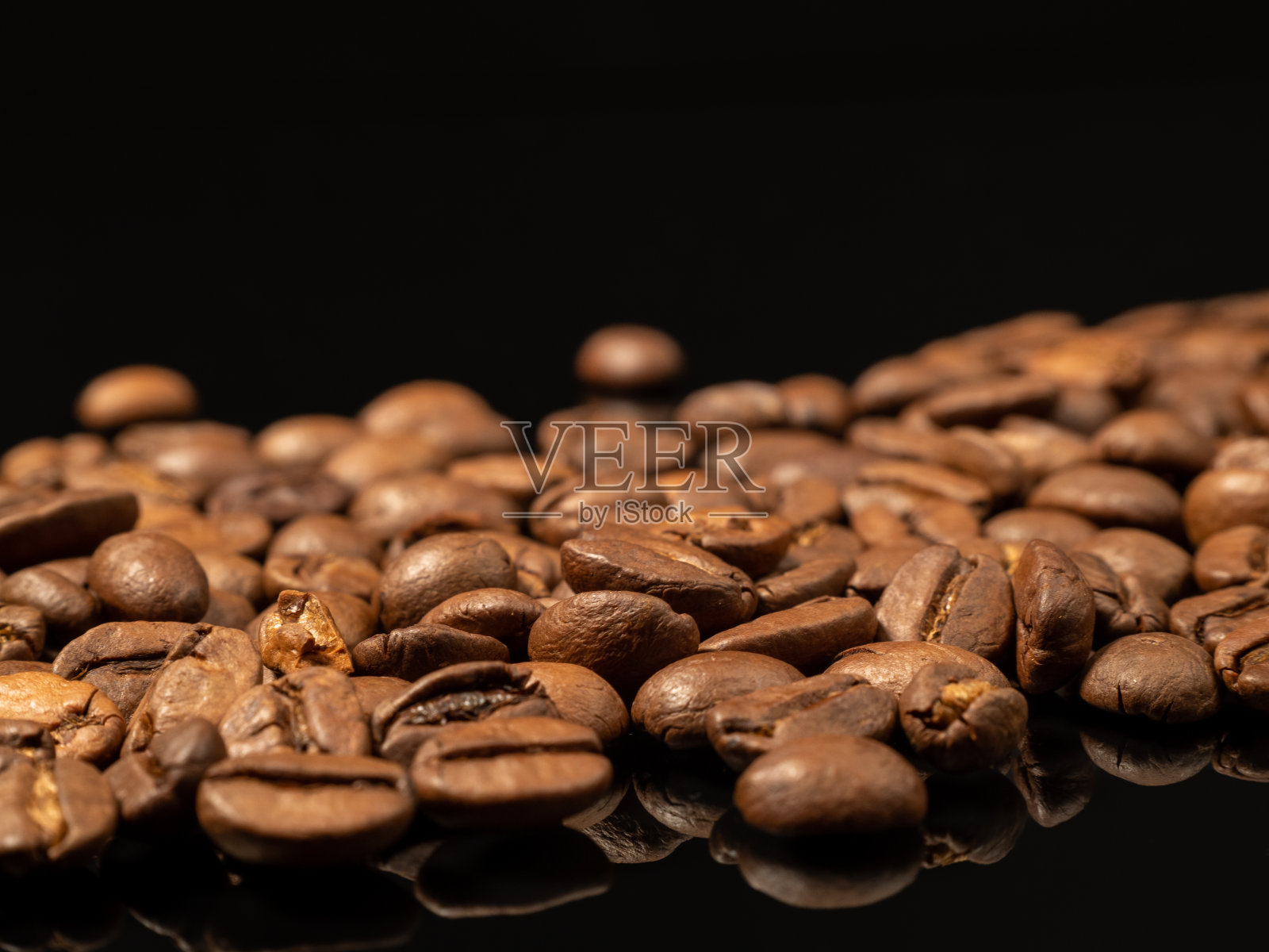 黑玻璃上烤过的咖啡豆。散落的咖啡豆。照片摄影图片