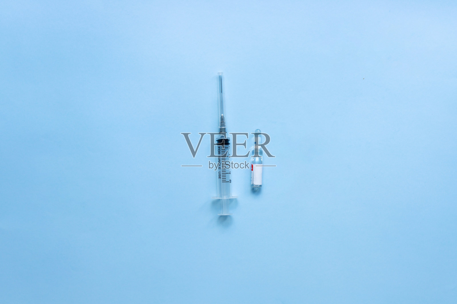 把疫苗平放在蓝色背景上。平放安瓿和注射器。照片摄影图片