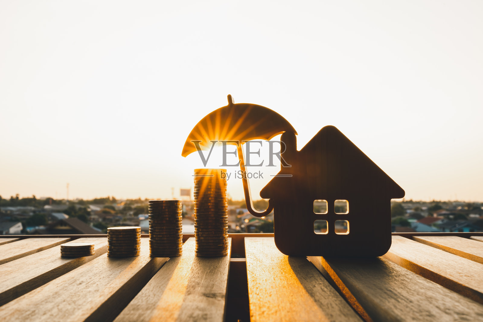 模型伞用房子和木桌上的硬币概念的保险制度，节省了健康保险的费用照片摄影图片