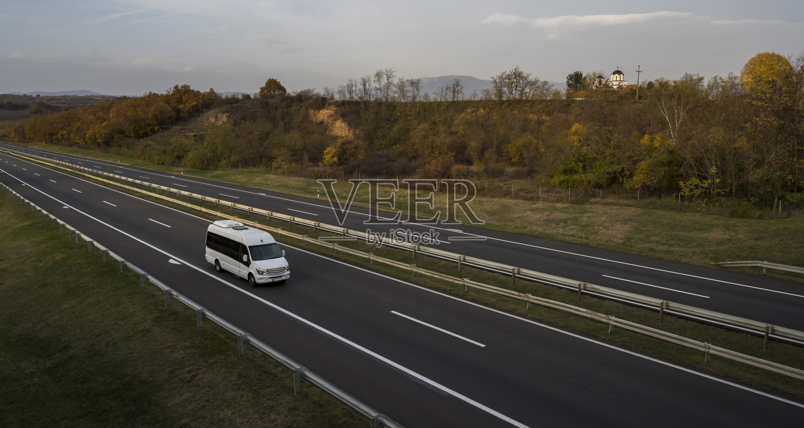 白色现代舒适的旅游巴士行驶在高速公路上。旅游和旅游车旅游的概念。乘车旅行和旅行。照片摄影图片