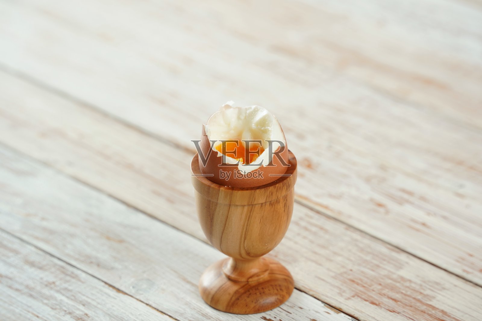 木制蛋杯中的溏心蛋，呈现流动的黄色蛋黄照片摄影图片