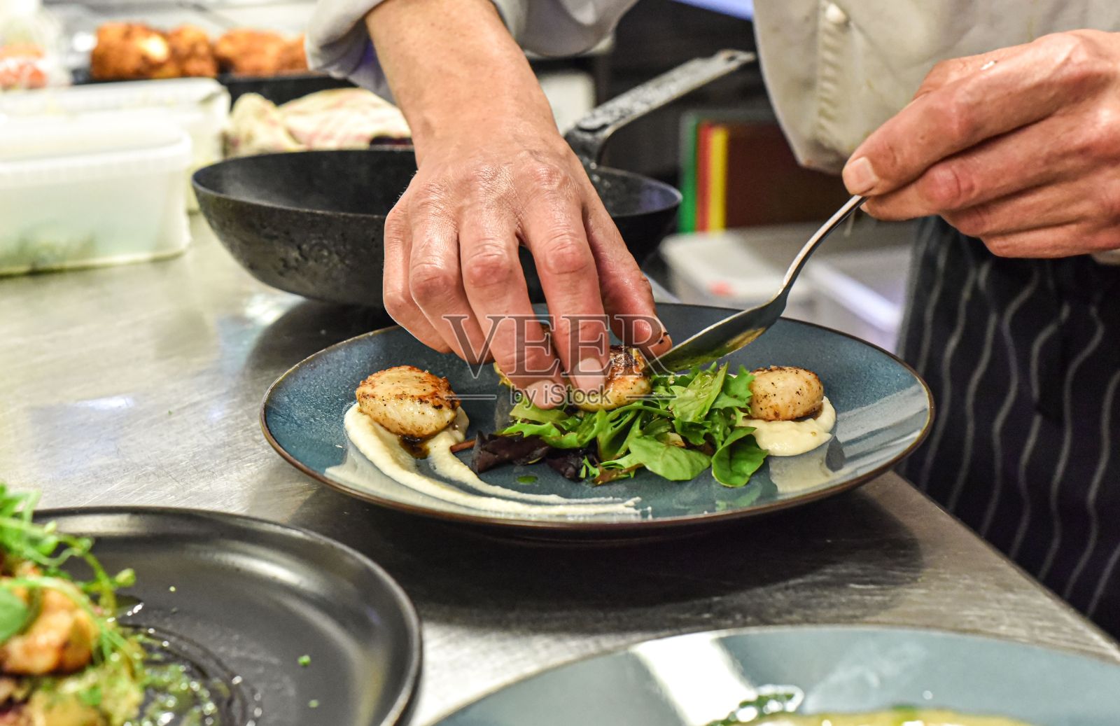 年轻的成年男子在厨房里，自信而熟练地把食物放在盘子里照片摄影图片