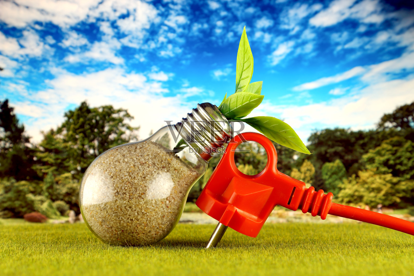 以田野和蓝天为背景的灯泡内的插头和植物生长。生态可再生能源概念。电价降，节能在户。照片摄影图片