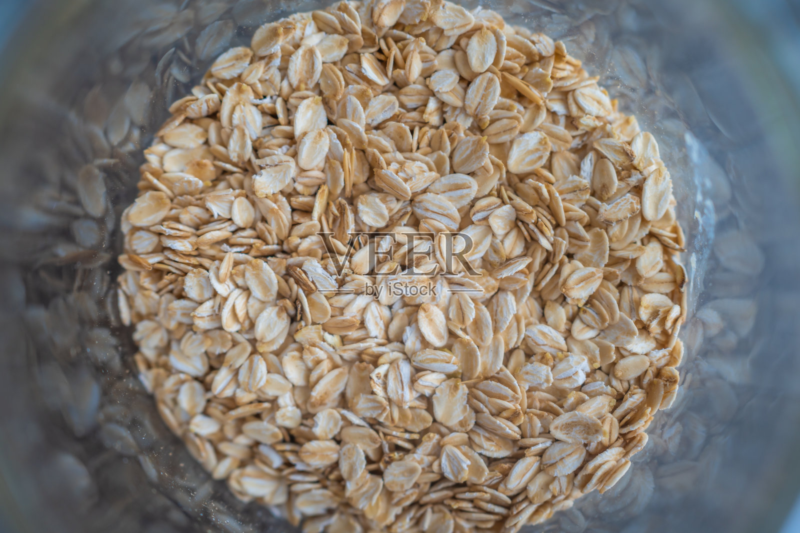 玻璃碗里的燕麦片(俯视图)。在灰色背景上。照片摄影图片