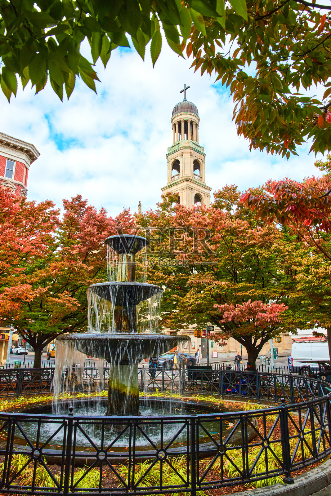美丽的小公园有喷泉，周围有秋天的树，后面是纽约格林威治村的基督教教堂尖塔。jpg照片摄影图片