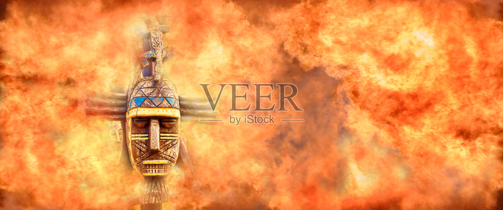 古老原始的木制面具周围是一堵坚固的火焰墙照片摄影图片