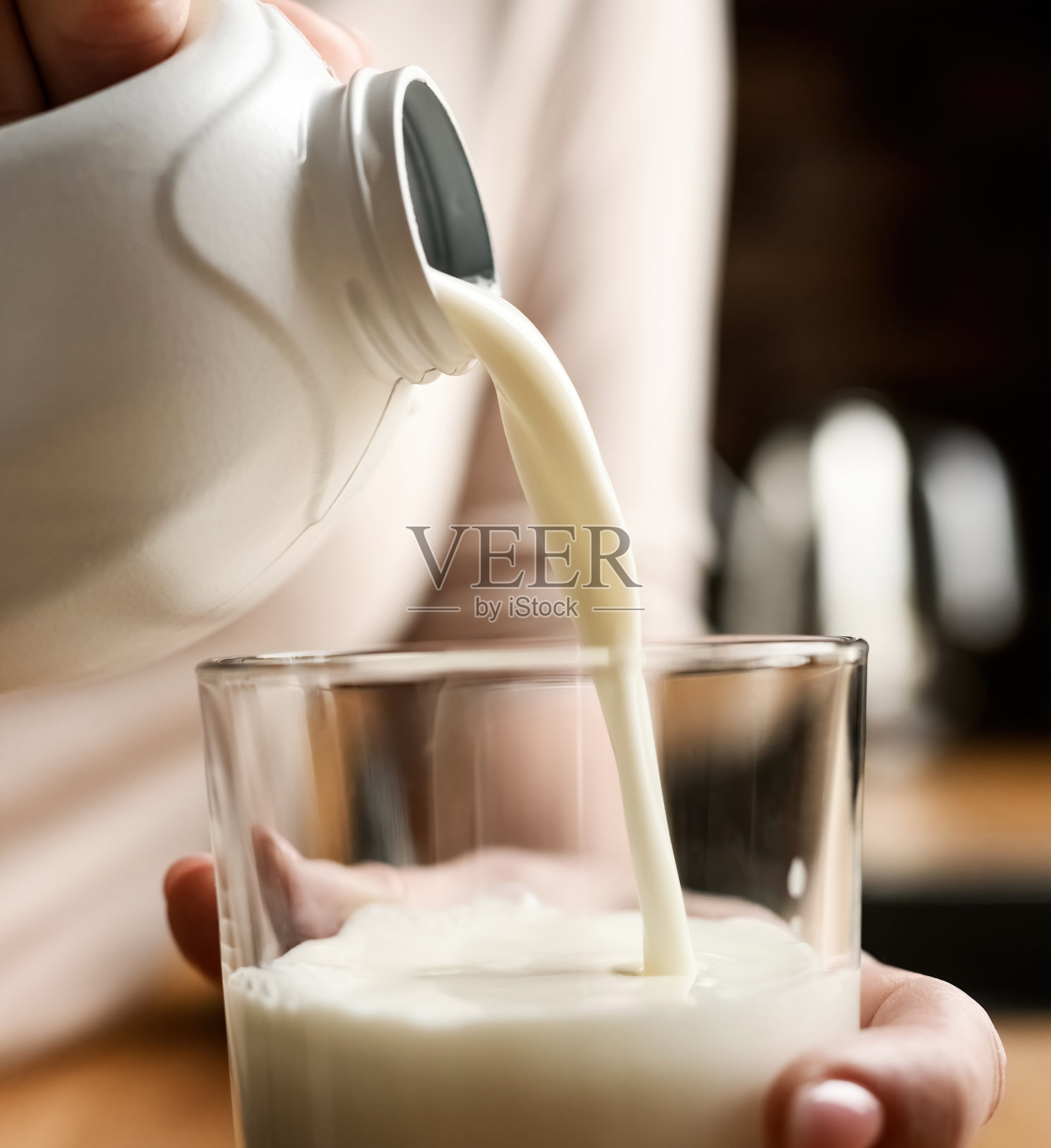 在家里的厨房里倒牛奶的女孩照片摄影图片