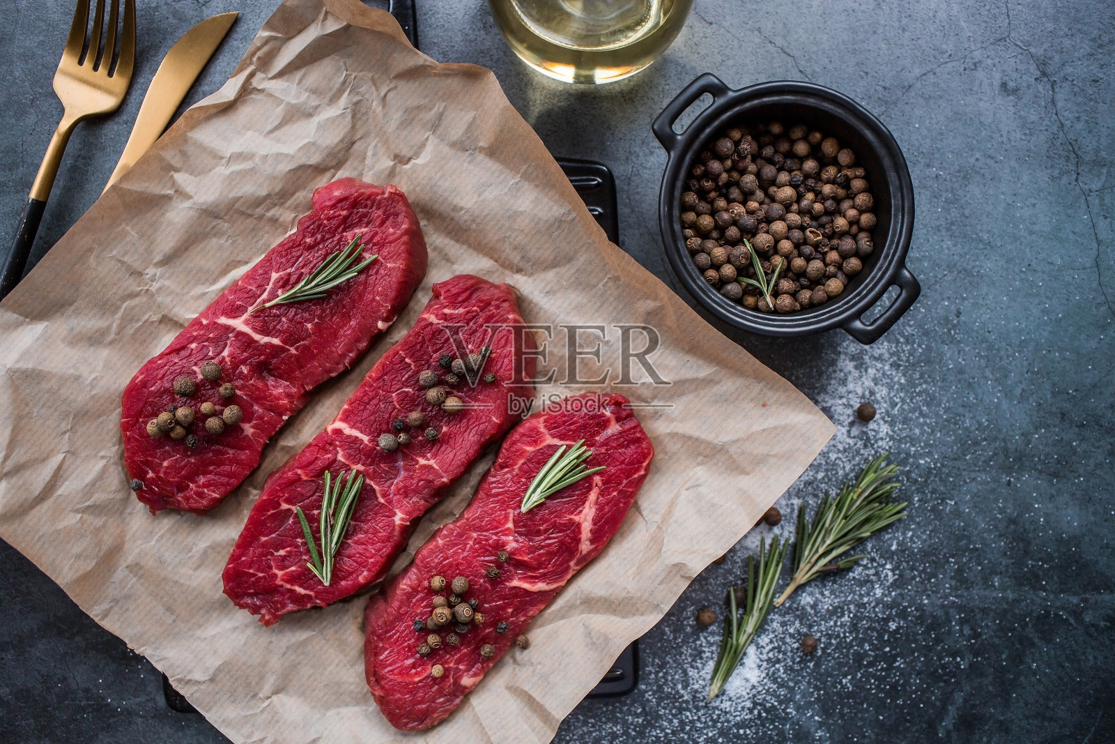 新鲜的肉。生牛排，加入迷迭香和香料，放在羊皮纸上。平顶视图。照片摄影图片