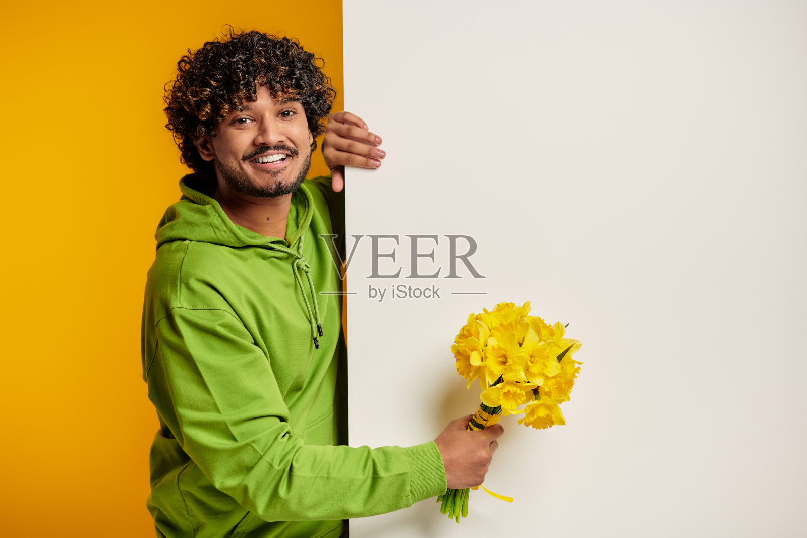 英俊的印度男子手持花束，背景是彩色的照片摄影图片