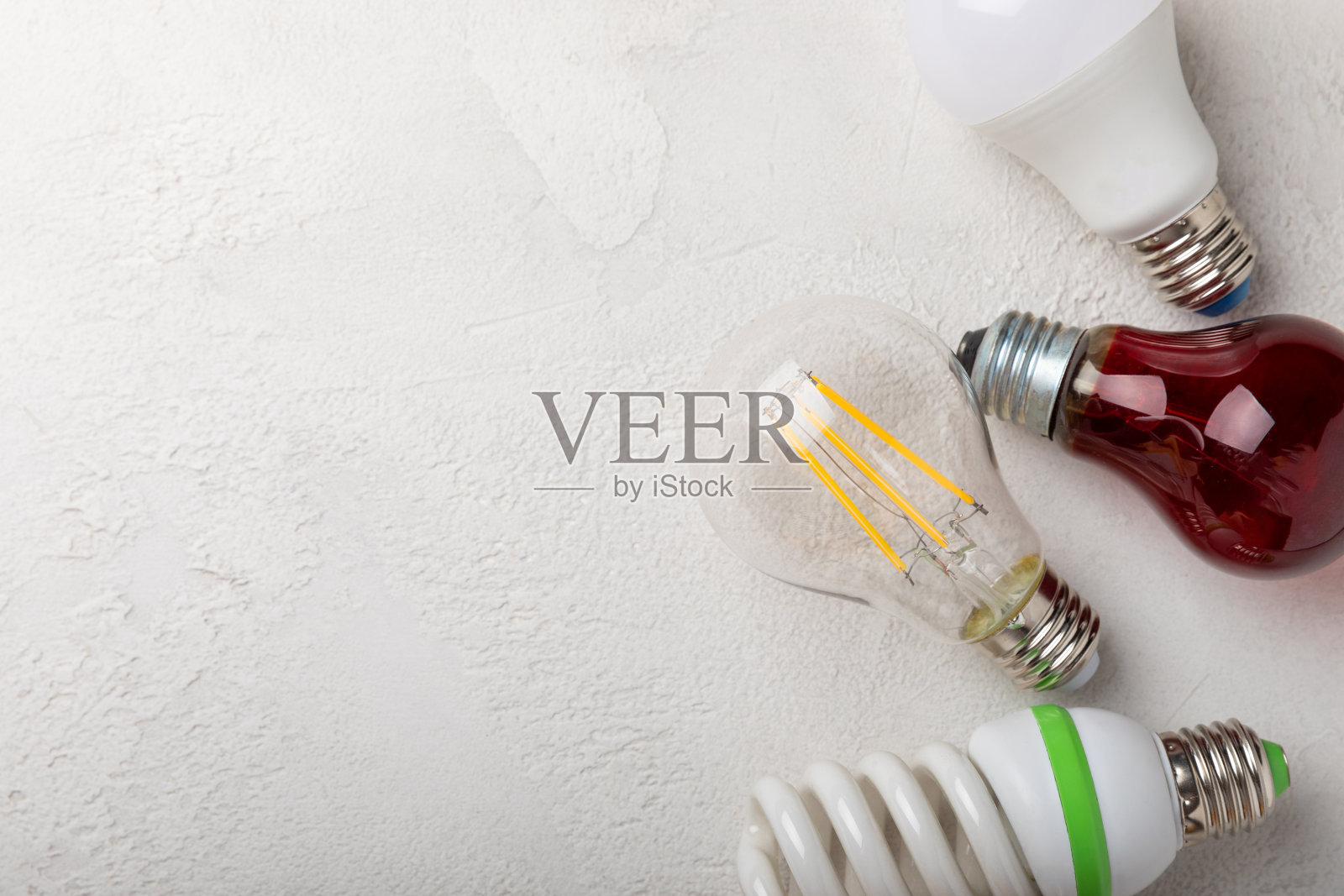 电灯泡。能源效率的概念。LED灯vs白炽灯。灰色水泥背景上的构图。使用经济环保的灯泡概念。照片摄影图片