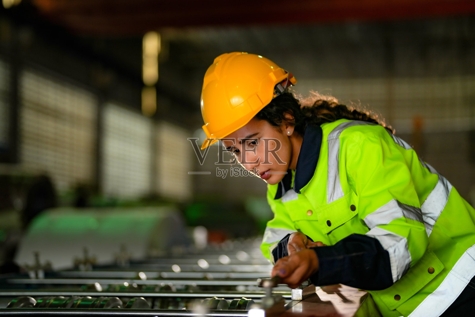 工厂工程师巴西妇女在重型工厂检查和修理机器。工人在工业工厂的重型机器旁工作。具有机械设备厂技术。照片摄影图片