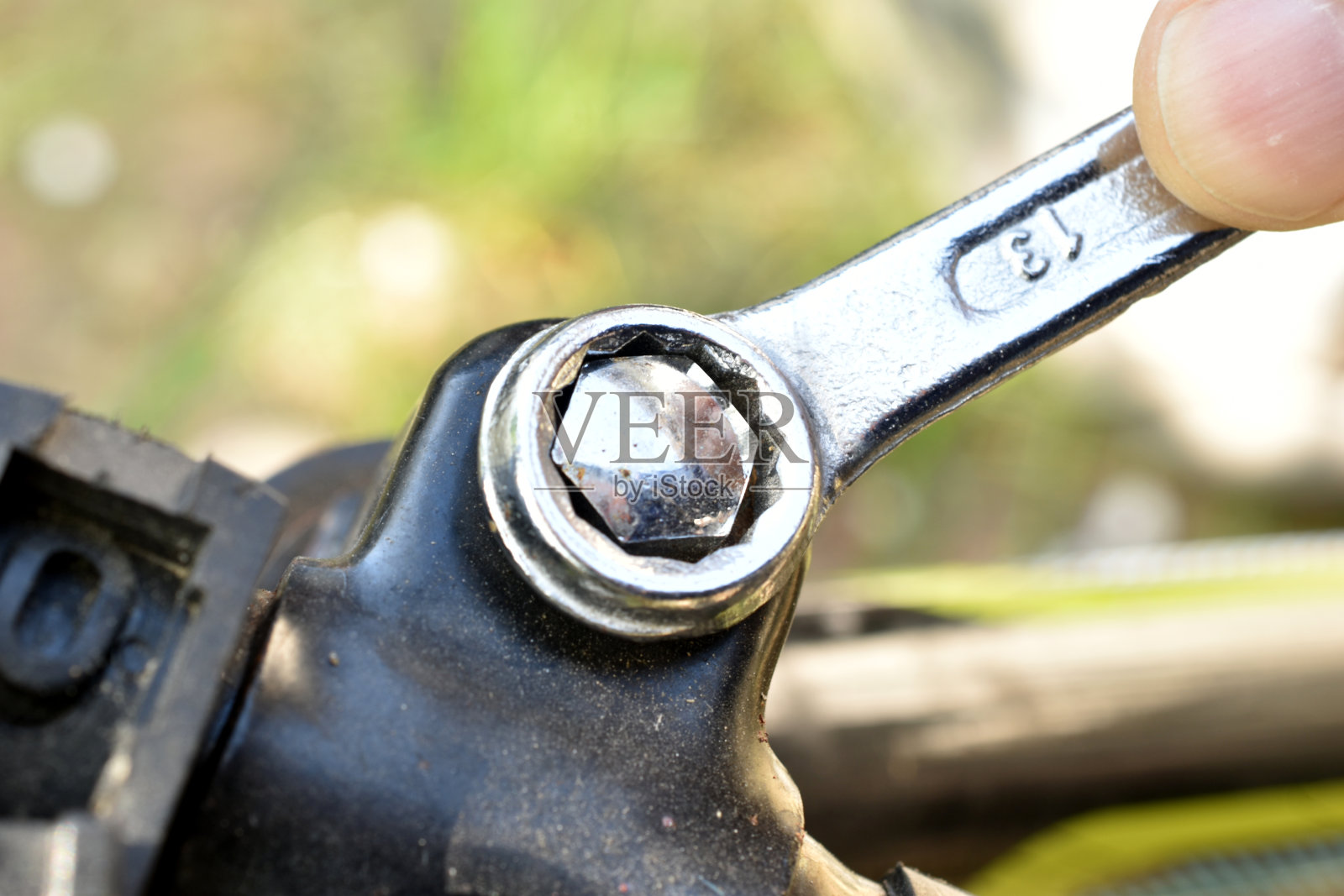 用环形扳手拧紧自行车车把螺栓的人的手。照片摄影图片