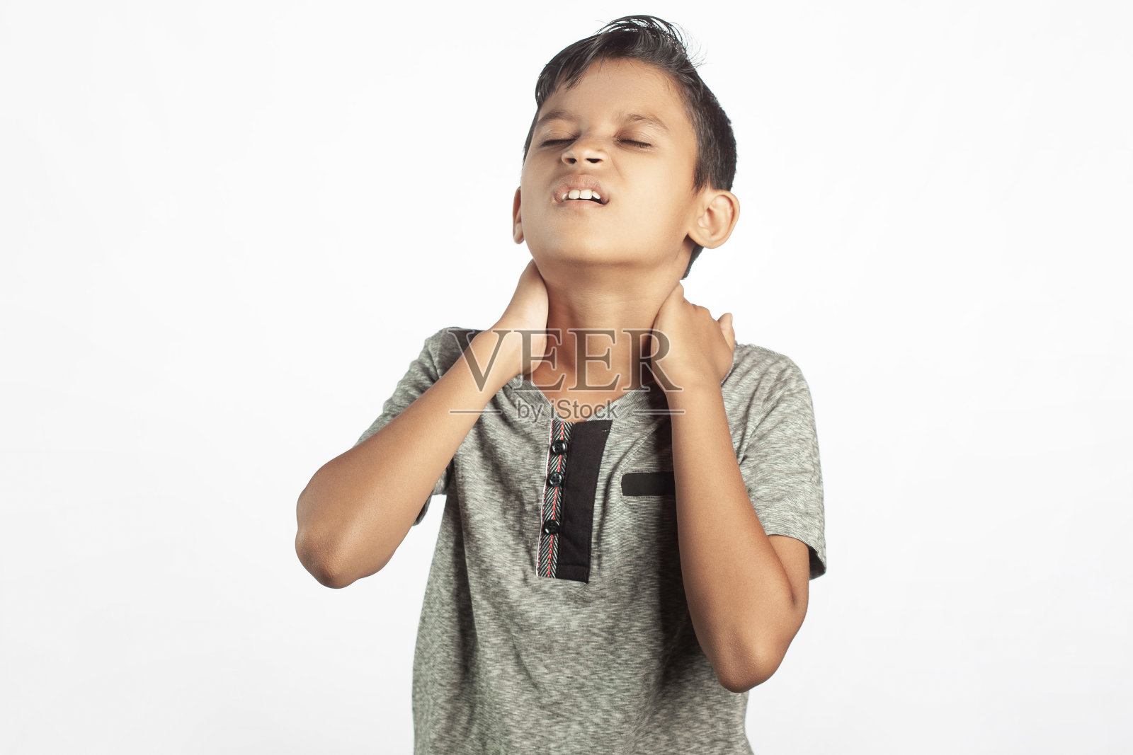 一个站在白色背景下的印度男孩正在经历颈部疼痛照片摄影图片